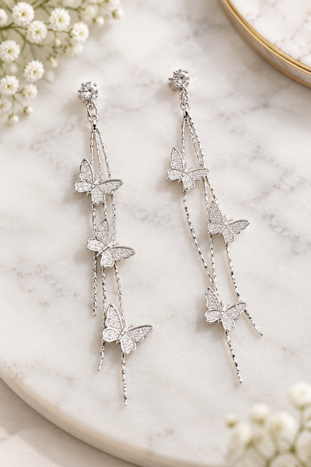 Silver butterfly cascade drop earrings on marble