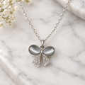 Crystal bow ribbon pendant necklace on white marble