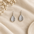 Silver teardrop drop earrings flat lay on linen