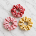 Set of 3 red pink and yellow gingham scrunchies on white marble