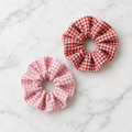 Set of 2 red and pink gingham scrunchies on white marble
