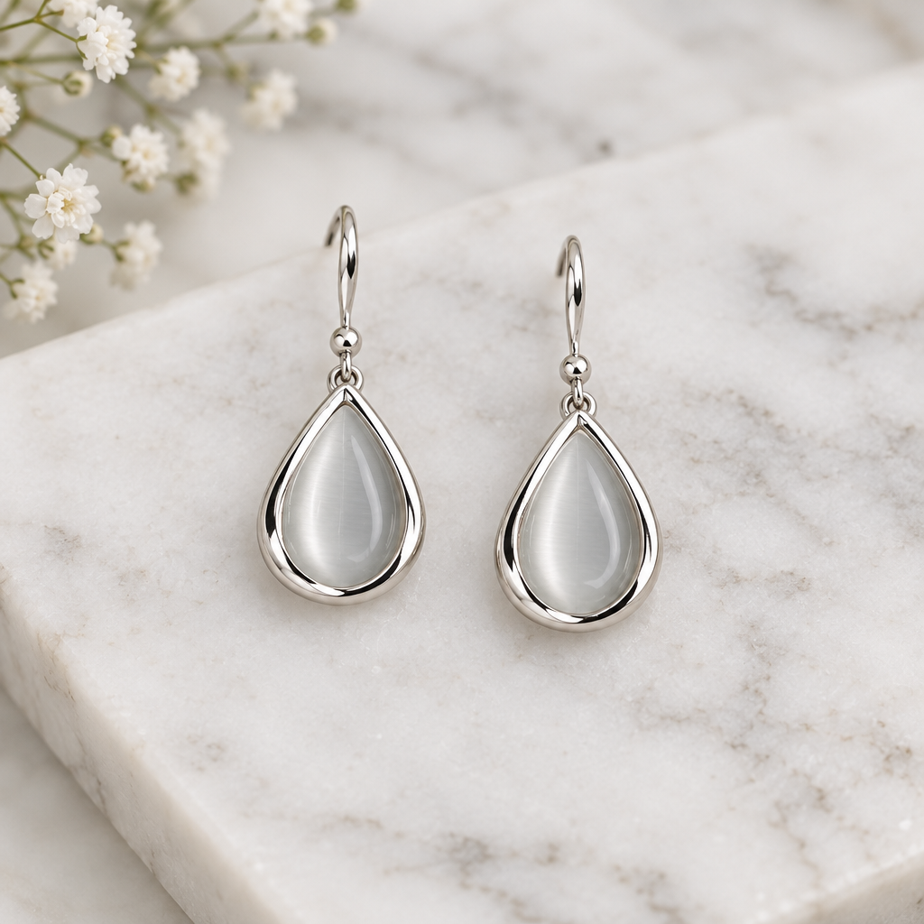 Silver teardrop drop earrings on white marble