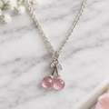 Pink cherry pendant necklace on white marble