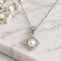 Pearl diamond halo pendant necklace on white marble